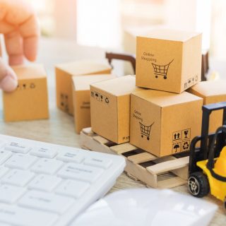 Mini forklift truck load cardboard boxes with symbols on wood pallet and fingers touch box and keyboard nearby. Logistics and transportation management ideas and Industry business commercial concept.